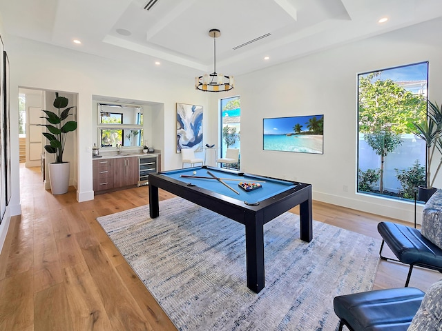 game room featuring a tray ceiling, recessed lighting, visible vents, light wood-style flooring, and beverage cooler