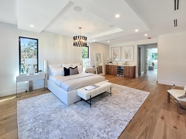 bedroom featuring recessed lighting, a raised ceiling, light wood-style floors, beverage cooler, and baseboards