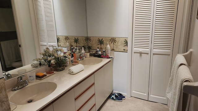 full bathroom featuring a sink, double vanity, toilet, and a closet