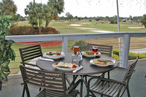 balcony with outdoor dining area and golf course view