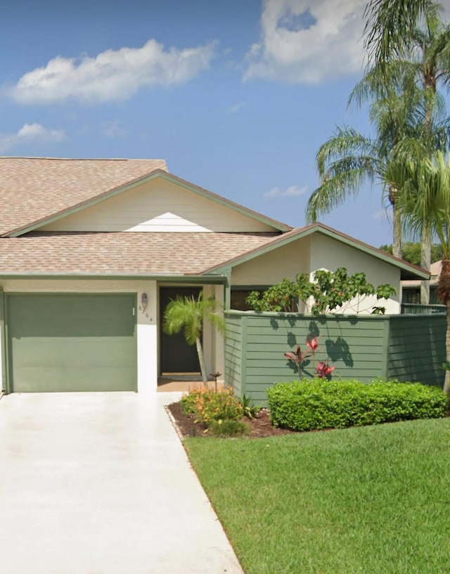 view of front of property with a garage, driveway, roof with shingles, and a front yard