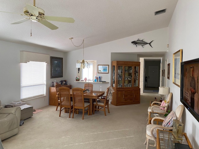 dining area with lofted ceiling, light carpet, visible vents, and a textured ceiling