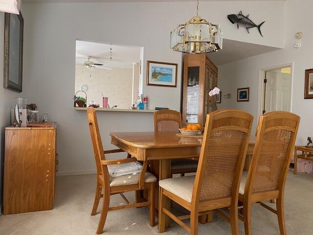 dining room featuring light carpet and ceiling fan with notable chandelier