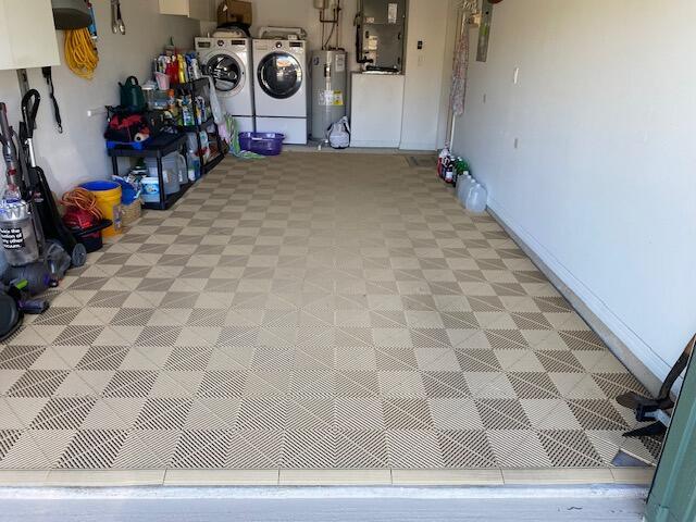 garage featuring washer and dryer, baseboards, electric water heater, and heating unit