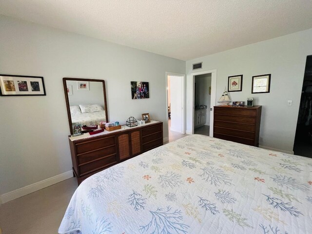 bedroom with visible vents, a textured ceiling, and baseboards