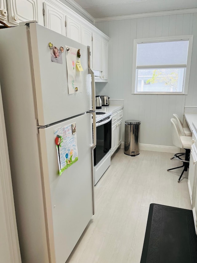 kitchen featuring electric stove, ornamental molding, freestanding refrigerator, light countertops, and white cabinetry