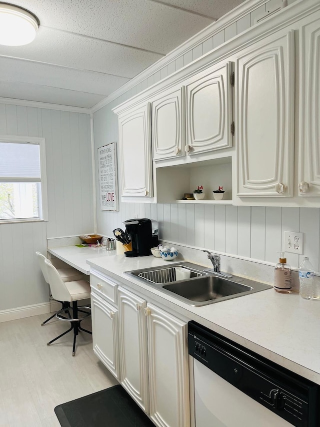 kitchen featuring white cabinets, white dishwasher, light countertops, and a sink