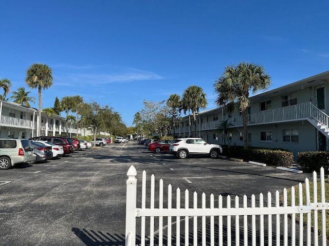 uncovered parking lot featuring a residential view and fence