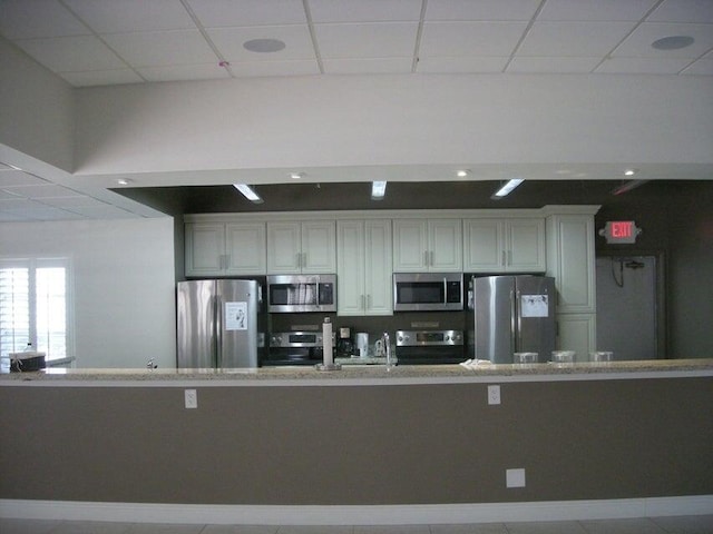 kitchen featuring light countertops, appliances with stainless steel finishes, a paneled ceiling, and white cabinetry