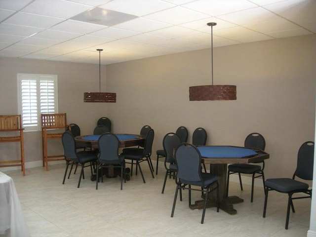 dining area featuring baseboards and a drop ceiling