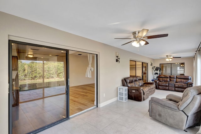 living room with light tile patterned flooring, ceiling fan, and baseboards