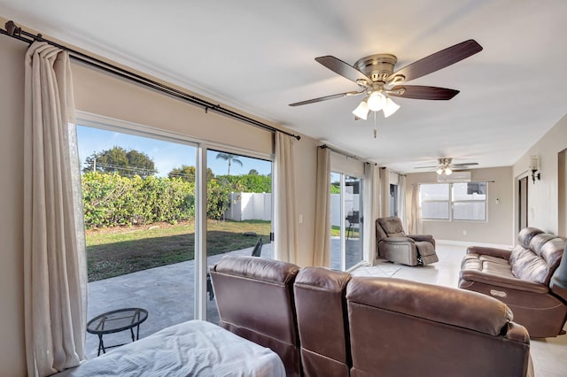 living area with a ceiling fan, tile patterned flooring, plenty of natural light, and baseboards