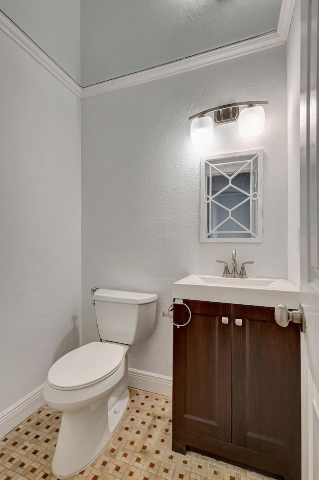 half bathroom with vanity, toilet, and baseboards