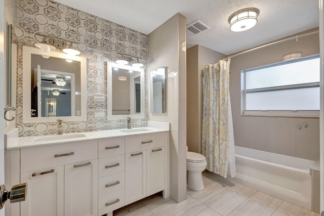 bathroom with double vanity, visible vents, toilet, a sink, and wallpapered walls