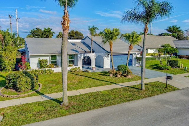 ranch-style house with concrete driveway, a front lawn, an attached garage, and stucco siding