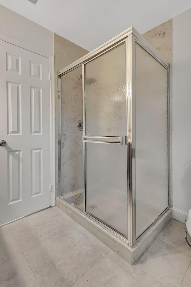 bathroom with a stall shower and tile patterned flooring