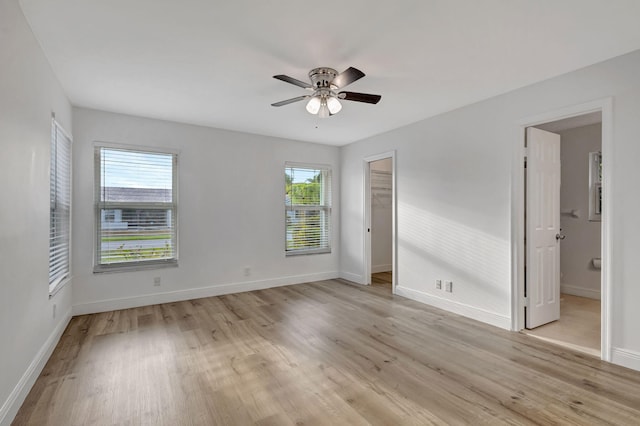 empty room featuring light wood-type flooring, a ceiling fan, and baseboards