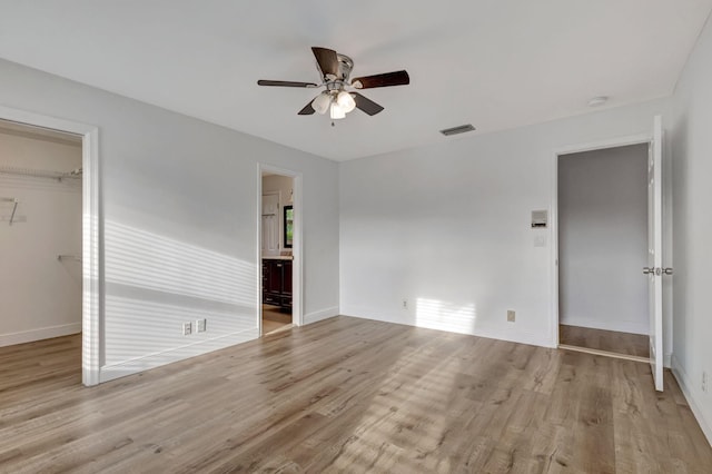 interior space with a closet, visible vents, a spacious closet, wood finished floors, and baseboards