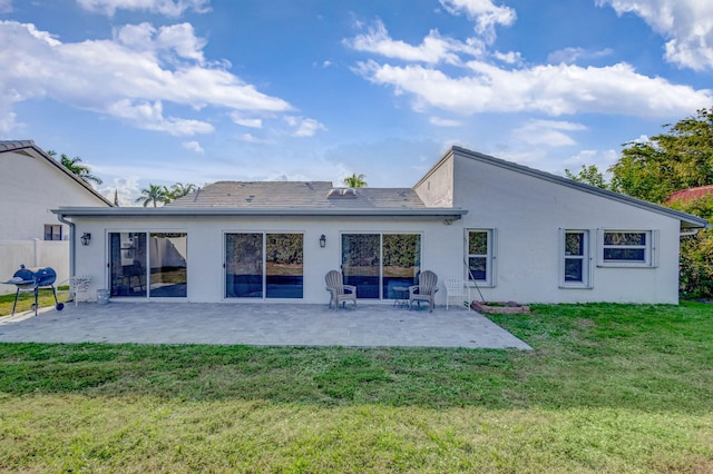 rear view of house featuring stucco siding, a lawn, and a patio