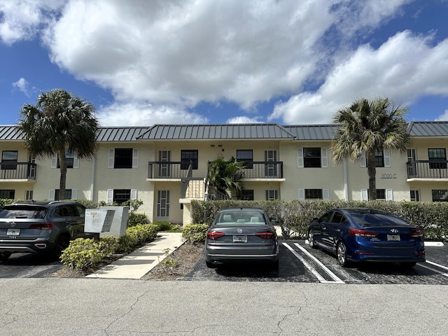 exterior space featuring uncovered parking, a standing seam roof, metal roof, and stucco siding