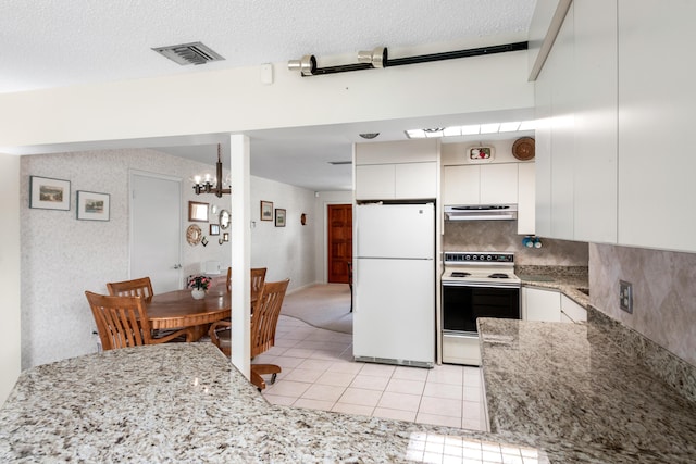 kitchen featuring visible vents, electric stove, freestanding refrigerator, ventilation hood, and white cabinetry