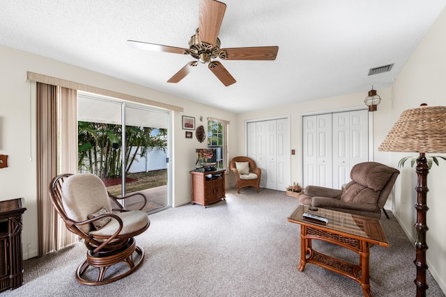 sitting room featuring a textured ceiling, carpet flooring, visible vents, and a ceiling fan