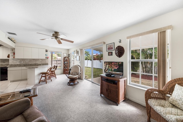 living room with light carpet, ceiling fan, visible vents, and a textured ceiling