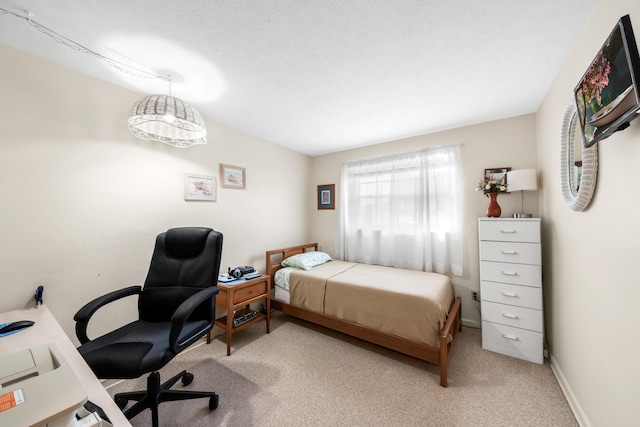 bedroom featuring light colored carpet, a textured ceiling, and baseboards