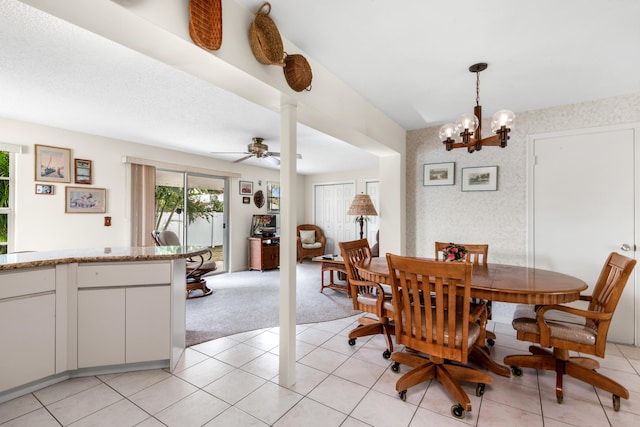 dining room featuring light carpet, wallpapered walls, light tile patterned floors, and ceiling fan with notable chandelier