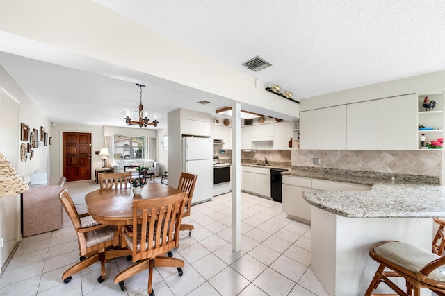 dining space featuring a textured ceiling, light tile patterned flooring, visible vents, and an inviting chandelier