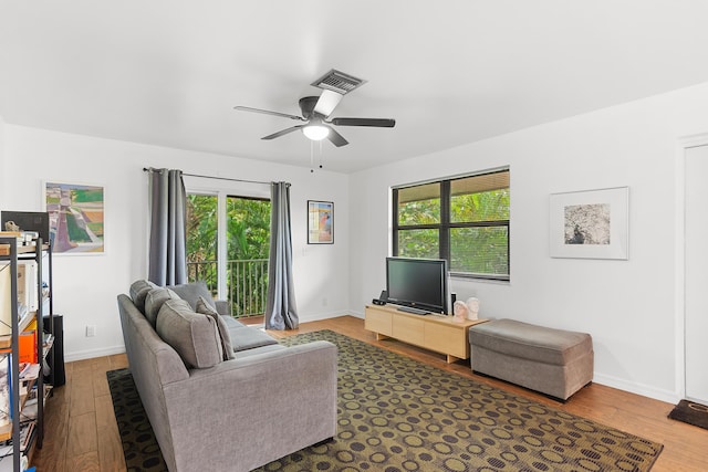 living room with visible vents, ceiling fan, baseboards, and wood finished floors