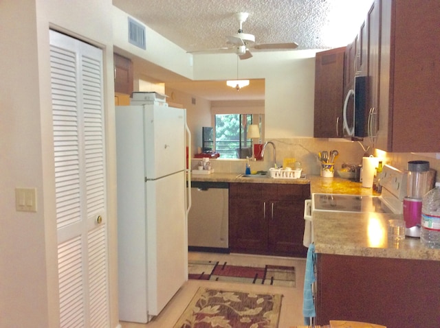 kitchen featuring dishwashing machine, stainless steel microwave, freestanding refrigerator, light countertops, and a sink