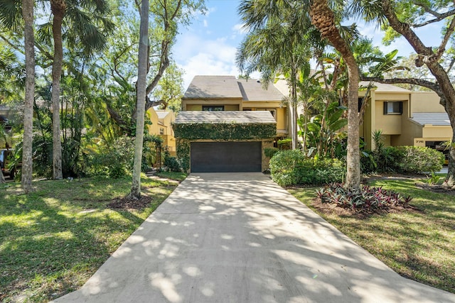 view of front of home featuring a garage, stucco siding, driveway, and a front yard