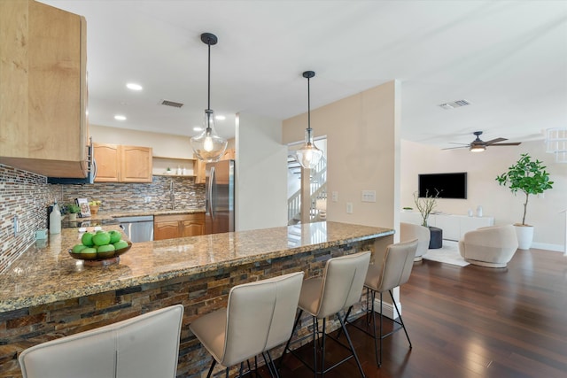 kitchen with light brown cabinetry, visible vents, stainless steel appliances, and decorative backsplash