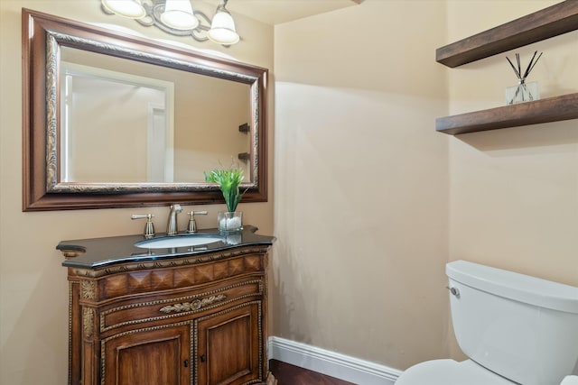 half bathroom featuring vanity, toilet, and baseboards