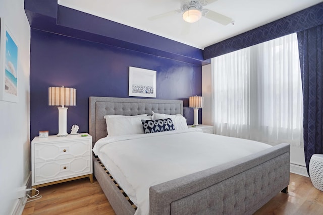 bedroom featuring a ceiling fan, multiple windows, and wood finished floors