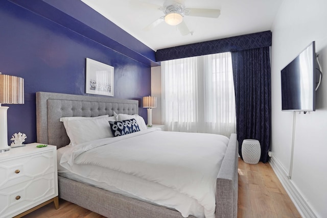 bedroom featuring a ceiling fan, baseboards, and wood finished floors