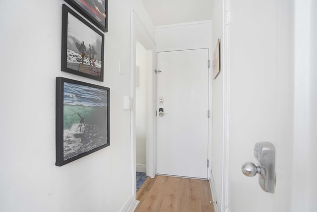 hall with light wood-style flooring and baseboards