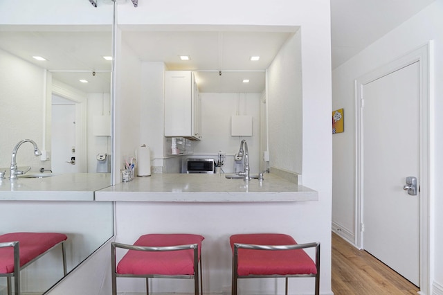 kitchen with a breakfast bar, white cabinets, a sink, and a peninsula