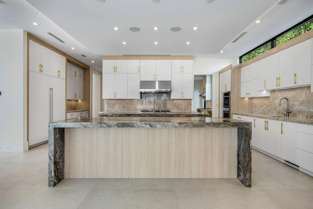 191 W Coconut Palm Rd, Boca Raton, FL 33432 - kitchen with paneled fridge, under cabinet range hood, a sink, decorative backsplash, and a large island with sink