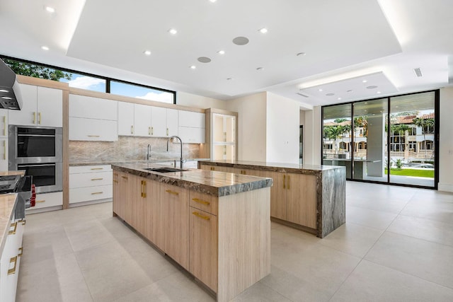 191 W Coconut Palm Rd, Boca Raton, FL 33432 - kitchen with a large island with sink, modern cabinets, a wall of windows, tasteful backsplash, and a sink