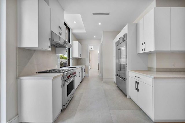 191 W Coconut Palm Rd, Boca Raton, FL 33432 - kitchen with high end appliances, wall chimney exhaust hood, a sink, backsplash, and white cabinets