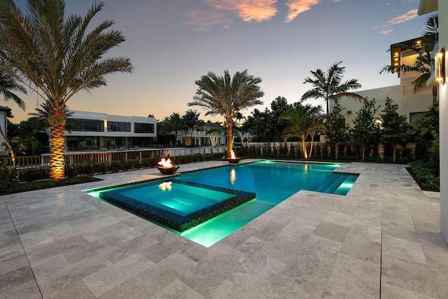 191 W Coconut Palm Rd, Boca Raton, FL 33432 - pool at dusk featuring a patio area, a pool with connected hot tub, and a fenced backyard