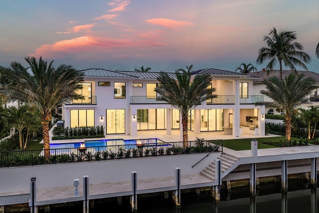 191 W Coconut Palm Rd, Boca Raton, FL 33432 - back of property at dusk featuring a standing seam roof, stucco siding, a patio, a balcony, and metal roof