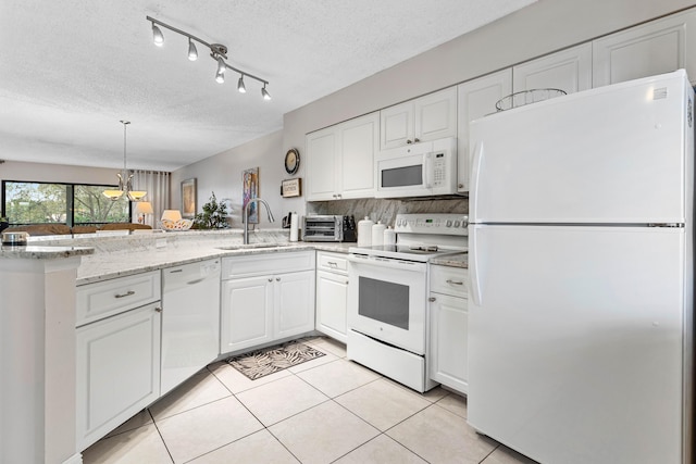 kitchen featuring light tile patterned flooring, a peninsula, white appliances, a sink, and white cabinetry