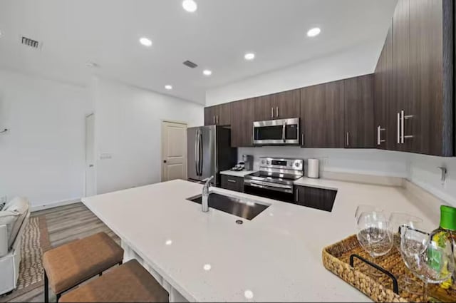 kitchen featuring visible vents, a peninsula, stainless steel appliances, light countertops, and a sink