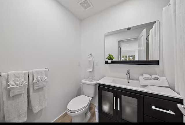 bathroom with baseboards, visible vents, vanity, and toilet