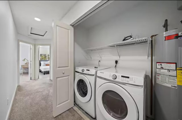 clothes washing area with electric water heater, light carpet, laundry area, washing machine and clothes dryer, and attic access