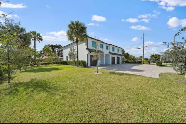 rear view of property featuring a garage, driveway, and a lawn