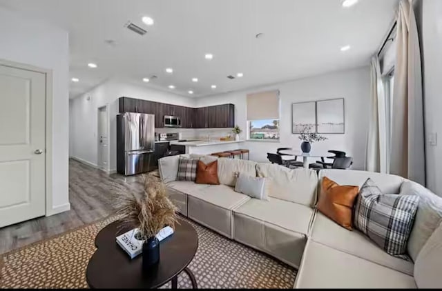 living area with light wood finished floors, visible vents, and recessed lighting